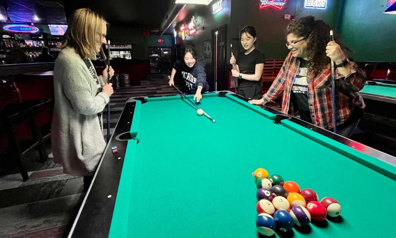 Angela Martino-Lewis (right) plays pool with several PSU international students at Opie’s Pizza Poolroom and Pub in Pittsburg.