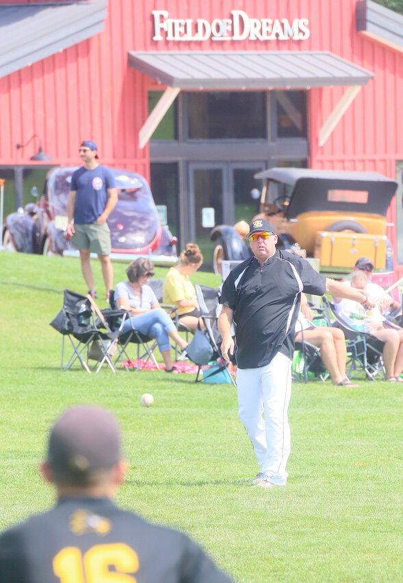 Central Lee assistant coach Ron Walker hits outfield balls to the Hawks at the Field of Dreams site in Dyersville prior to the Hawks' 12-2 victory over Pekin Monday.