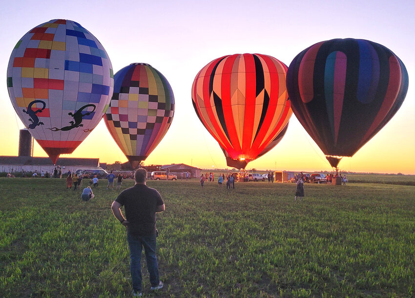 Harvestville Farms co-owner Adam Hohl takes a long look at the hot air balloons glowing against the sunset Saturday night in Donnellson. Hohl and his wife Julie put on the event for the first time at the farm.