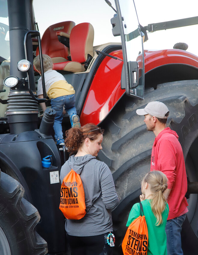 A youngster climbs into a farm tractor at the Fort Madison Elementary School's S.T.R.E.A.M. Night event Thursday outside the school. Grant Weisinger, in red, brought the tractor and was one of 40 vendors that participated.