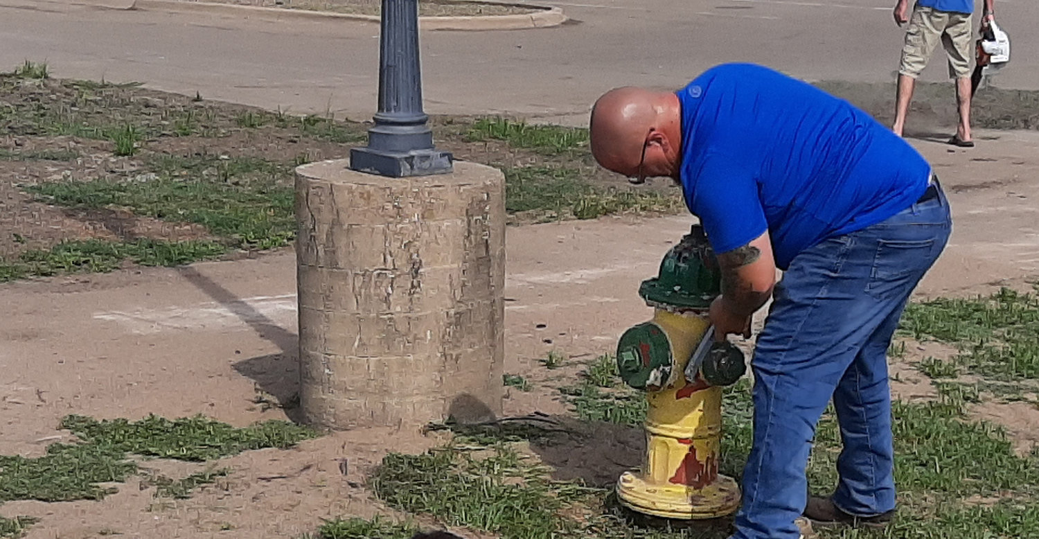 A volunteer worker scrapes the paint from a hydrant in Riverview Park Monday afternoon as part of a beautification effort in front of the inaugural American Cruise line arrivals on Tuesday. Photo by Chuck Vandenberg/PCC