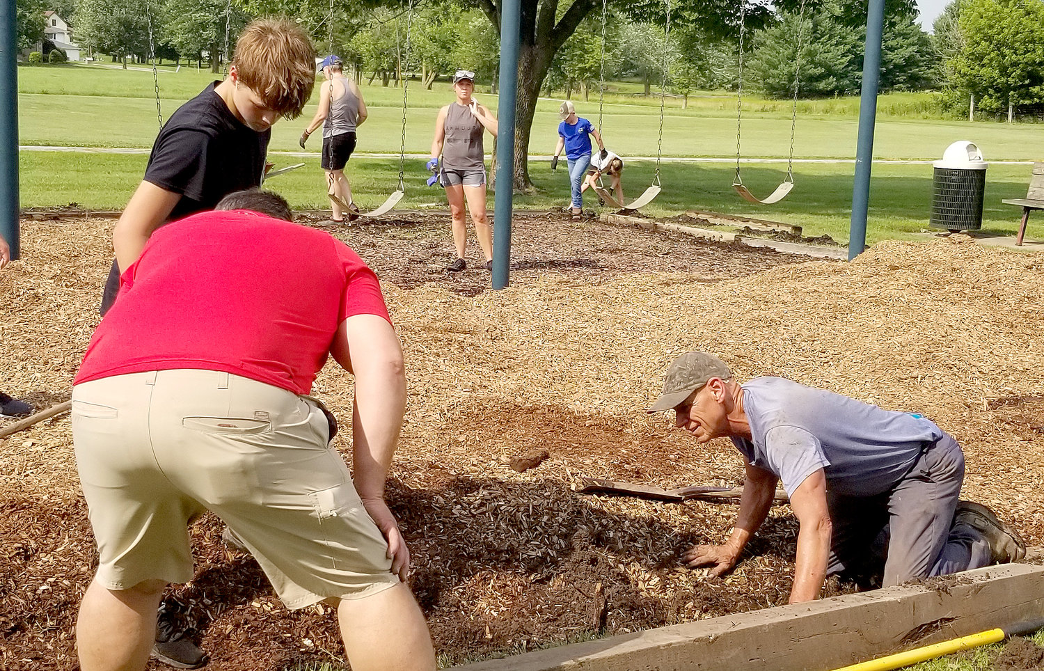 Volunteers work with West Point Public Works Director Flavian Boeding to add wood chips and timbers to the South Park playground equipment last week. Courtesy photo.