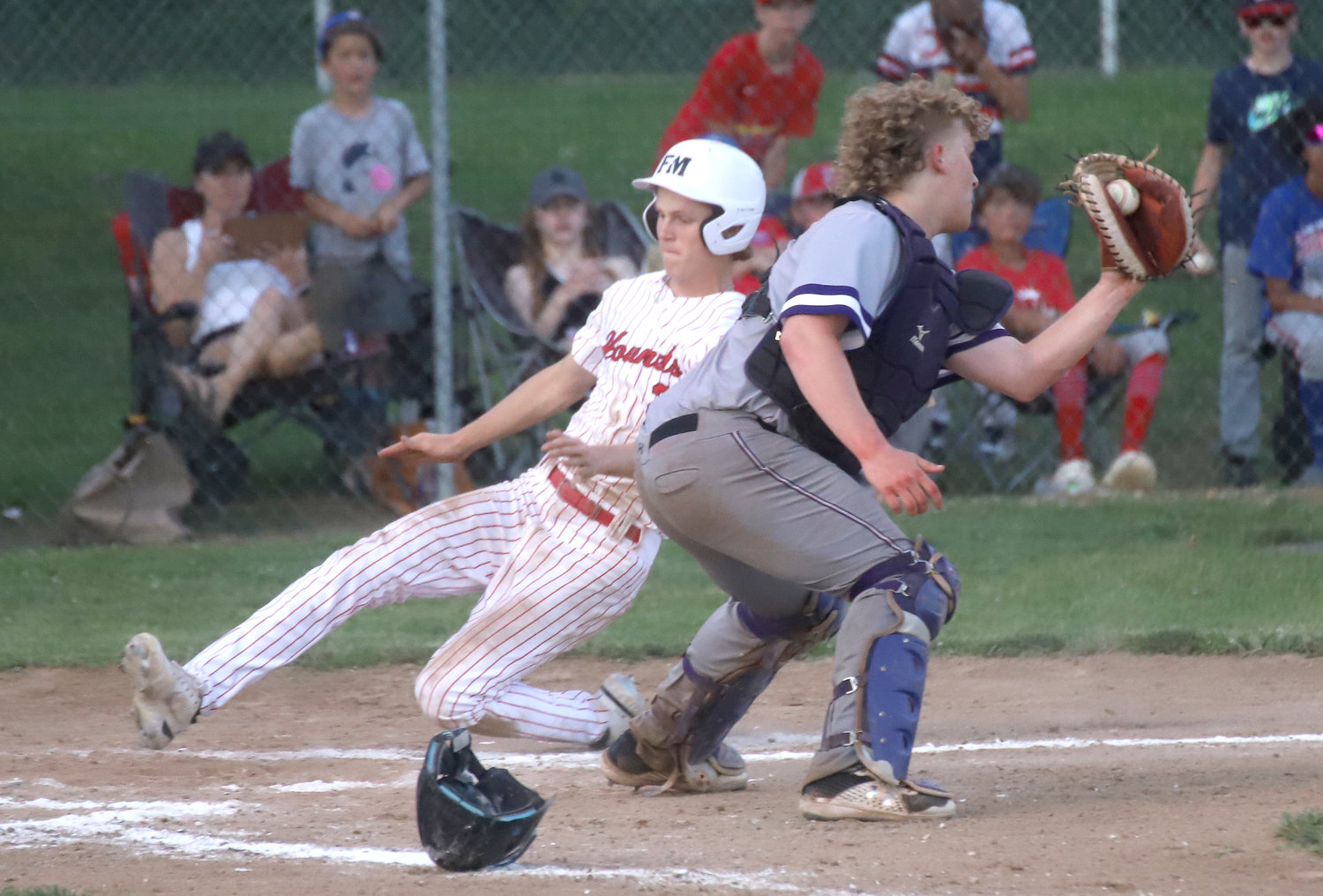 Fort Madison's Reiburn Turnbull slides into home in front of throw to Burlington catcher Tyce Bertlshofer in a 13-2 loss in game 2 of a doubleheader Monday night in Fort Madison. The Bloodhounds won game 1 5-4. Photo by Chuck Vandenberg/PCC