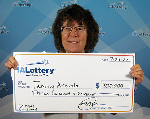Tammy Arevalo of Fort Madison holds up a promotional check from Iowa Lottery after cashing in a $300,000 Colossal Crossword scratch ticket she bought at Hy-Vee in Fort Madison. Arevalo also won $100,000 back in 2016.