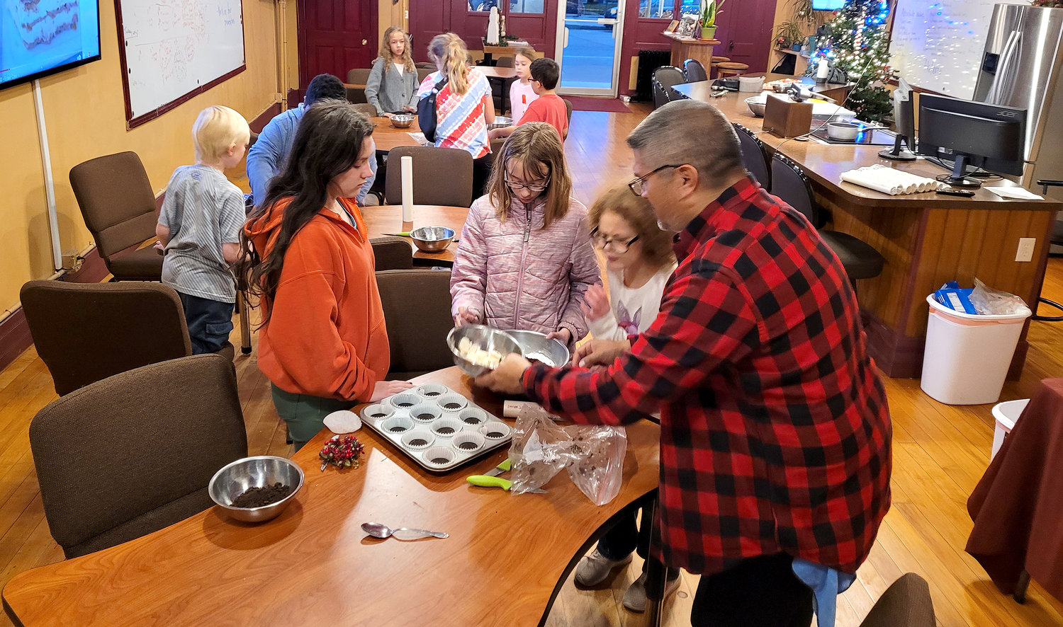 Elliott Test Kitchen's Brian Mendez works with students Monday night on some no-bake desserts. The Test Kitchen and Fort Madison YMCA announced a merger Monday morning.