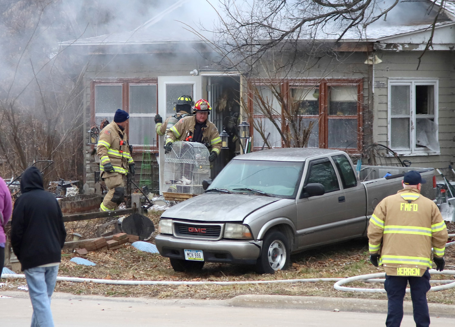 Fire Capt. Jay Blanchard carries a couple of live birds out of a burning home at 1623 33rd Street Thursday afternoon. The birds survived the blaze and no one was reported injured as a result of the fire in Fort Madison.