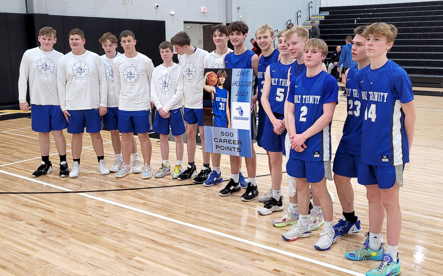 Luke Hellige, center, stands with a poster signifying his surpassing of the 500-point mark Tuesday night in the Crusaders' win over Central Lee.