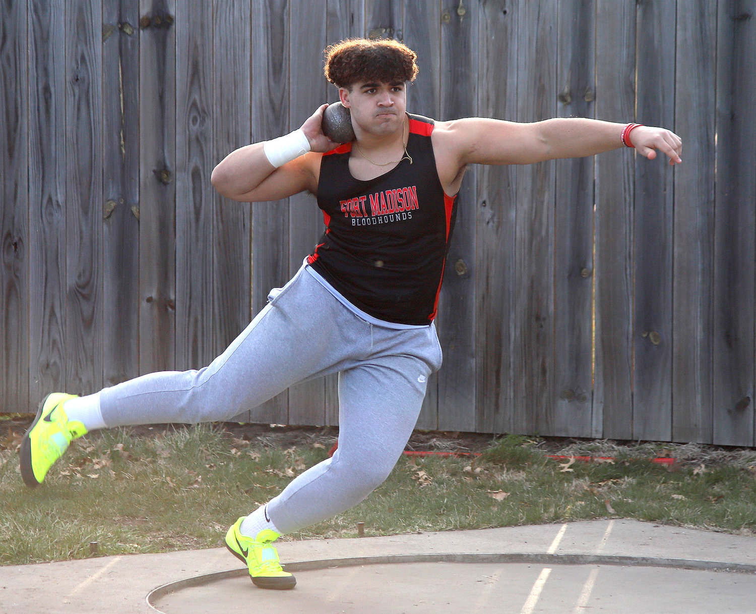 The Hounds' Caden Barnes winds up for a throw in the shot-put at Falcon Field Monday night. Barnes would earn 3rd in Class 3A.