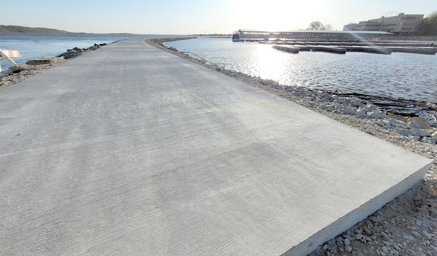 This vantage point shows the sun reflecting off the marina pool as the jetty wall wellness path stretches toward the river.