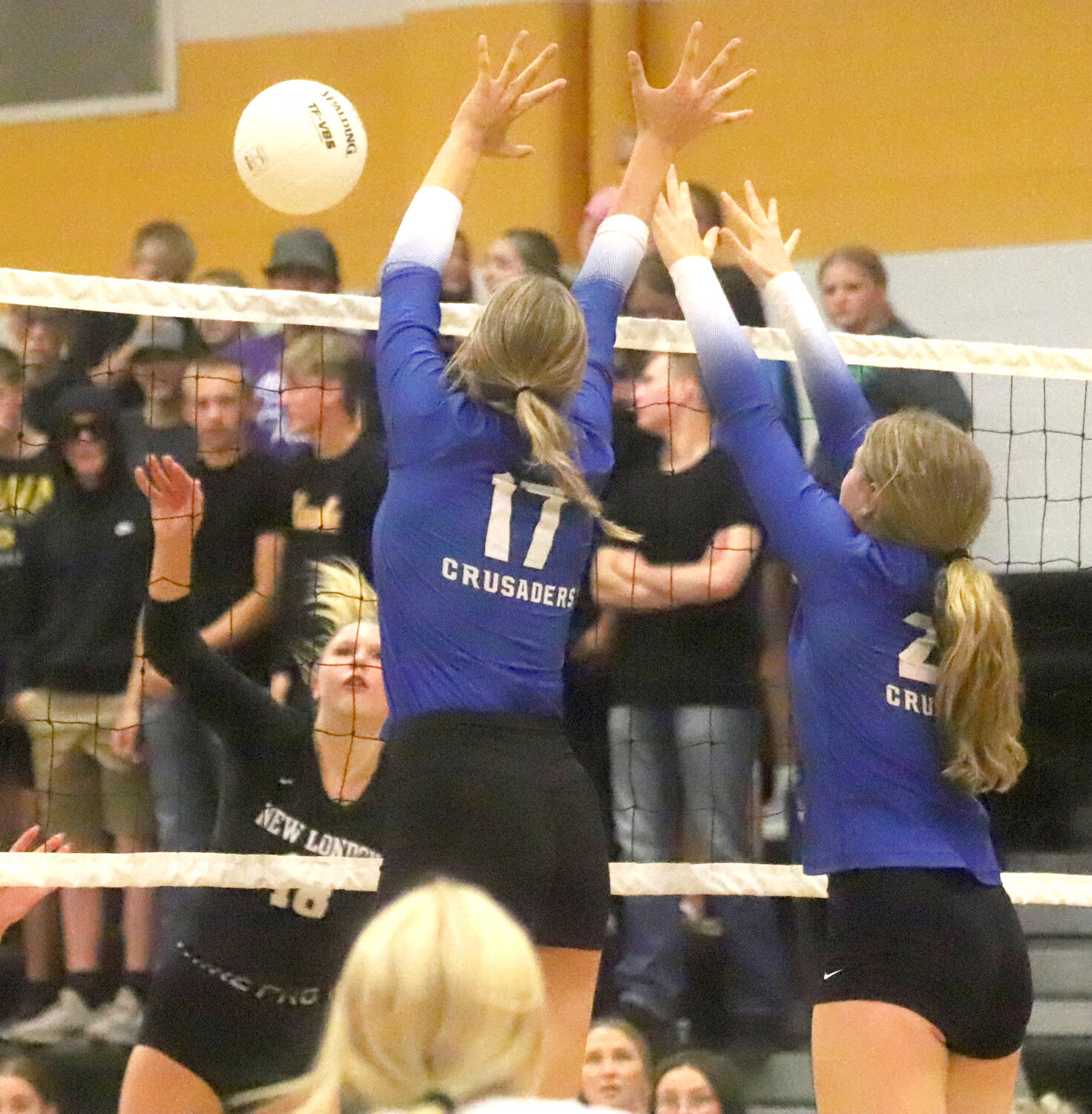 New London's Sophie Mallot (18) tries to drive a kill past HTC's Presley Myers (17) and Anna Bendlage (24). The Crusaders swept the Lady Tigers in three sets.