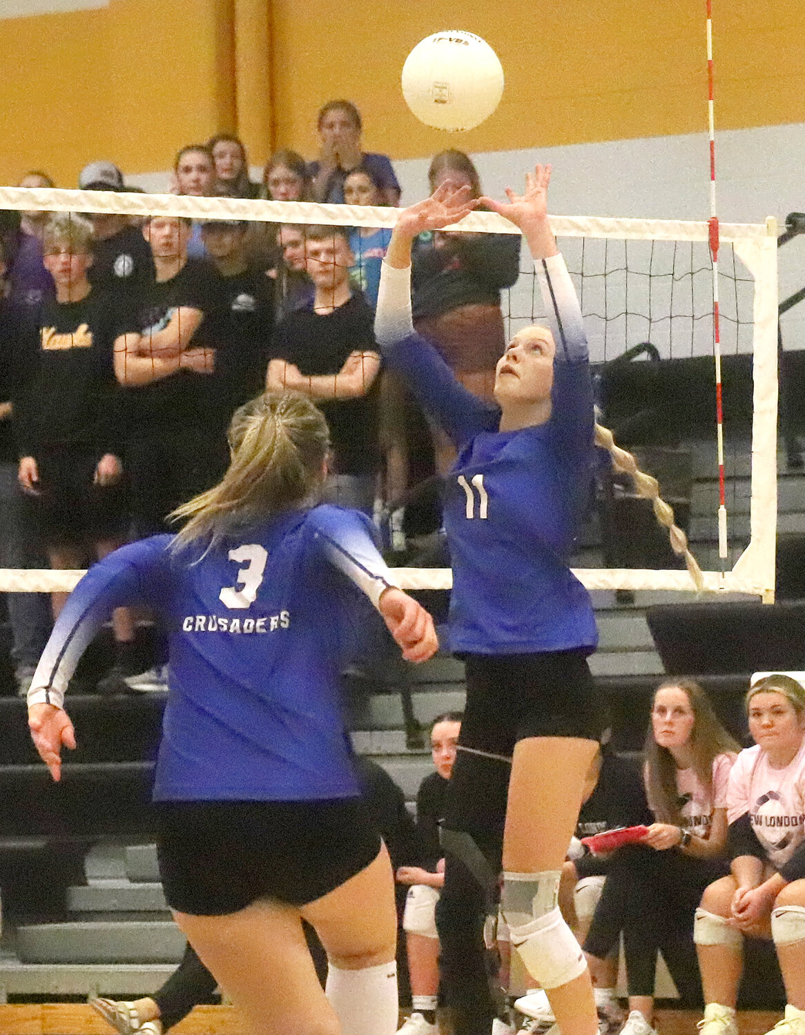 Senior Natalie Randolph gets a set going as freshman Adalyn Kruse rushes the net in third set action Tuesday in New London.