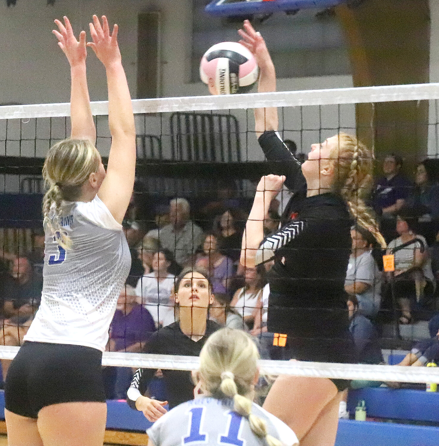 Adalyn Kruse (left) goes up to block an attack from Fort Madison's Sydney McEntee (right) in the first set of the Lady Hounds' match with Holy Trinity Catholic.