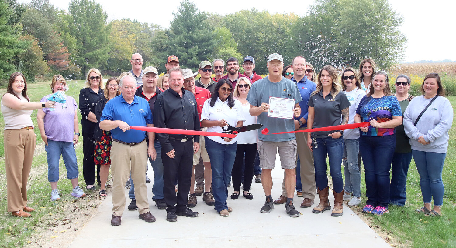 Fort Madison Chamber ambassadors and dignitaries help with a ribbon-cutting at the reconstructed Pollmiller Trail Wednesday afternoon.