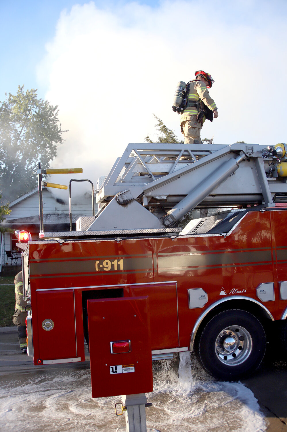 A lone FM Firefighter walks across the ladder assembly on top of a Fort Madison aerial fire truck before deploying to a home in the 3400 block of Avenue N.