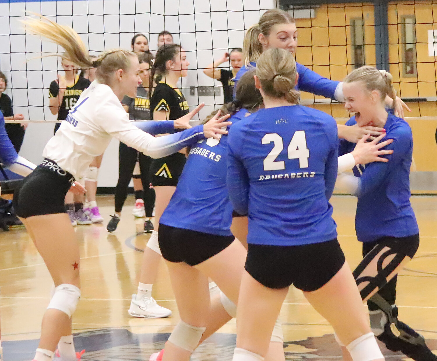 The HTC Crusaders 'gently' celebrate with senior Natalie Randolph after her kill sealed the win over Edgewood-Colesburg to advance to the state volleyball championships Tuesday night in Coralville. Randolph has been battling knee pain all season after missing last season with a surgical repair.