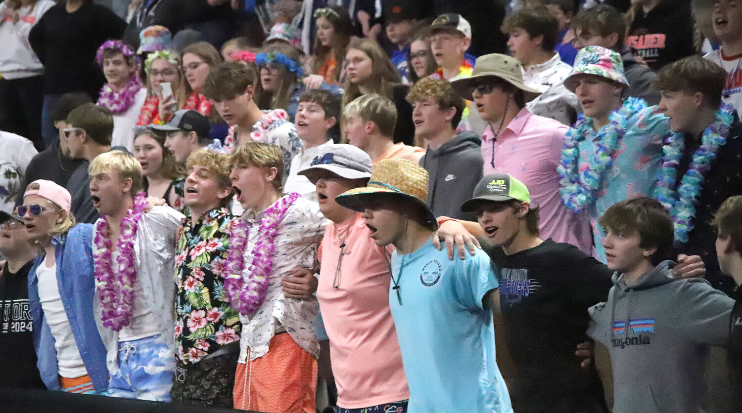 The student section decked out in beach garb cheers on the Crusaders at the Xtreme Arena in Coralville Tuesday night during the IGHSAU quarterfinals of the State Volleyball Tournament.