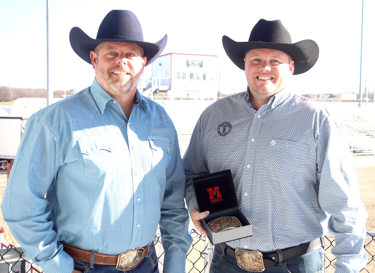 Past Tri-State Rodeo general chairman Tony Johnson, left, hands off the general chairman buckle to incoming general chairman Bobby Holtkamp Tuesday at the Tri-State Rodeo Arena.