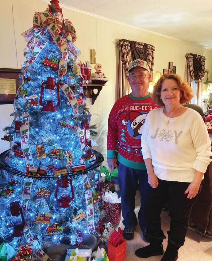 Bo and Alice Roy of Lumberton stand by their Christmas tree which is incorporated with trains, rails, red lanterns and other railroad-related items. PHOTO BY DANNIE OLIVEAUX | SILSBEE BEE