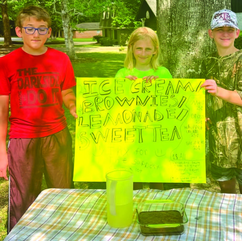 Bryce Pyne, JuJu Pyne, and Christopher Watson hold up sign for lemonade stand.