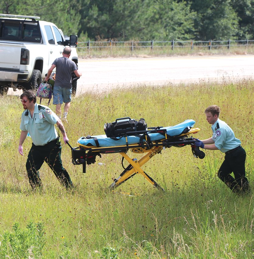 Ambulance workers make tracks as they head back to their vehicle after treating people involved in an accident Friday. In this case they got to treat one of their own because an ambulance was involved in the crash.
