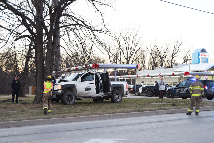 Members of the Harrisonville Fire Department and Police Department investigate an accident where a truck was driven head first into a tree near the Sonic restaurant Tuesday evening.