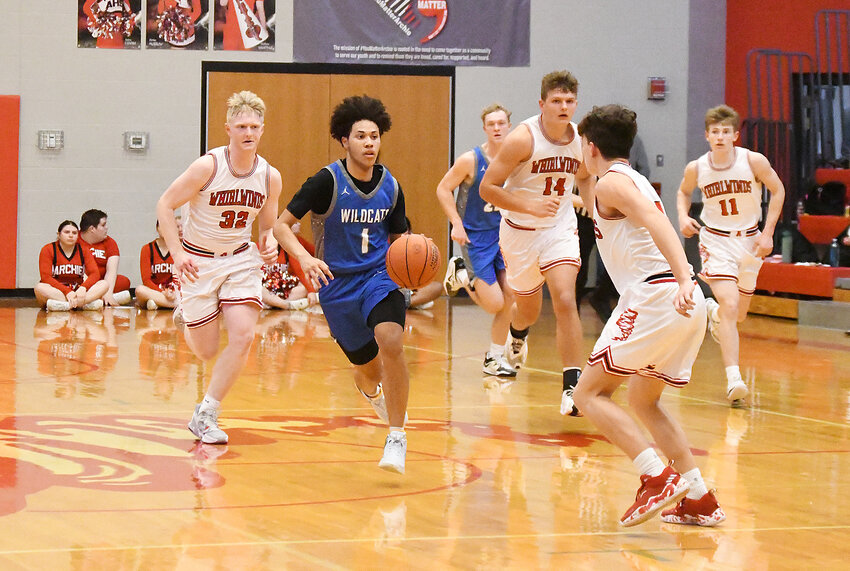 Harrisonville senior Dom Jackson (1) dribbles through Archie defenders during Friday’s game. Jackson scored 12 points in the Wildcats’ 65-42 victory.