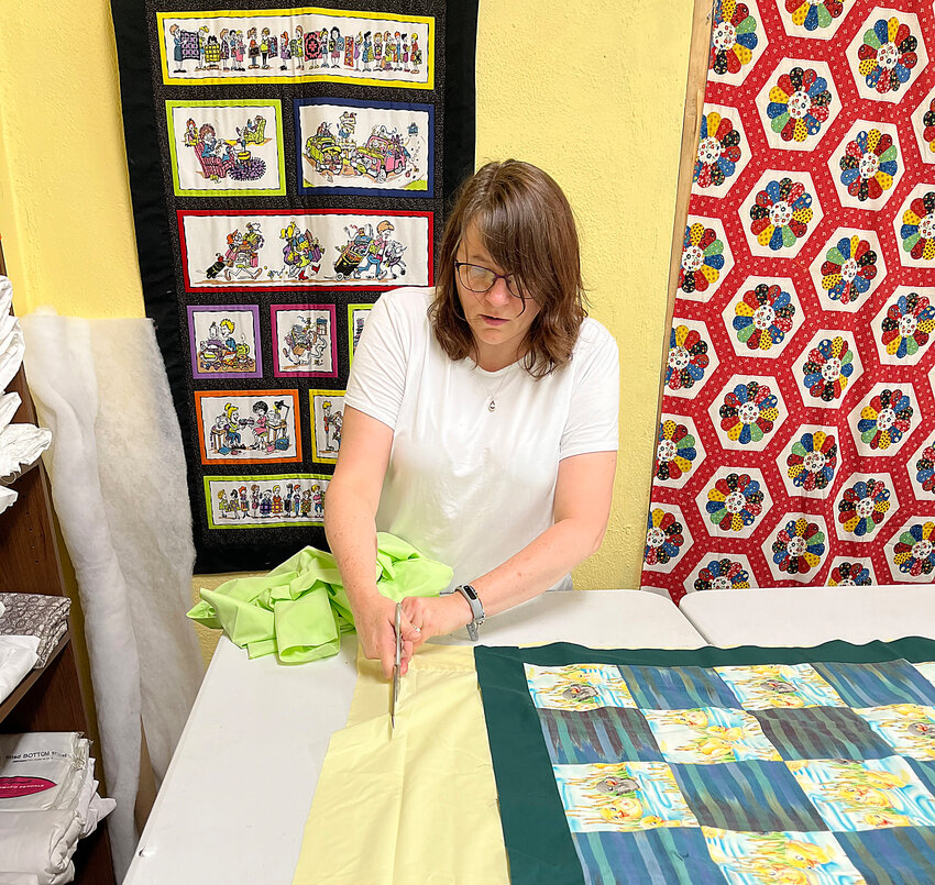 Comforting Angels volunteer Melanie Vance cuts a sheet to size for the underside of a new quilt.