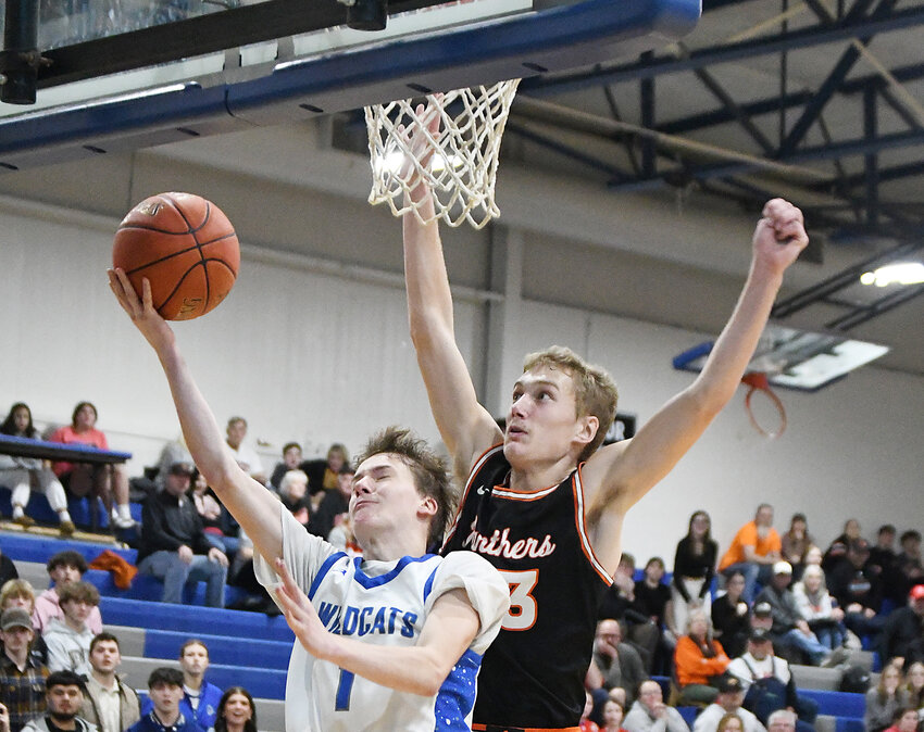 At left: Harrisonville sophomore Cole Smalley (20) scores a layup during Friday’s game against Oak Grove. Smalley scored 10 points in the Wildcats’ 68-62 overtime victory. Above: Harrisonville senior Eli Baker (1) shoots a contested layup late in Friday’s win. Baker led the Wildcats with 23 points.