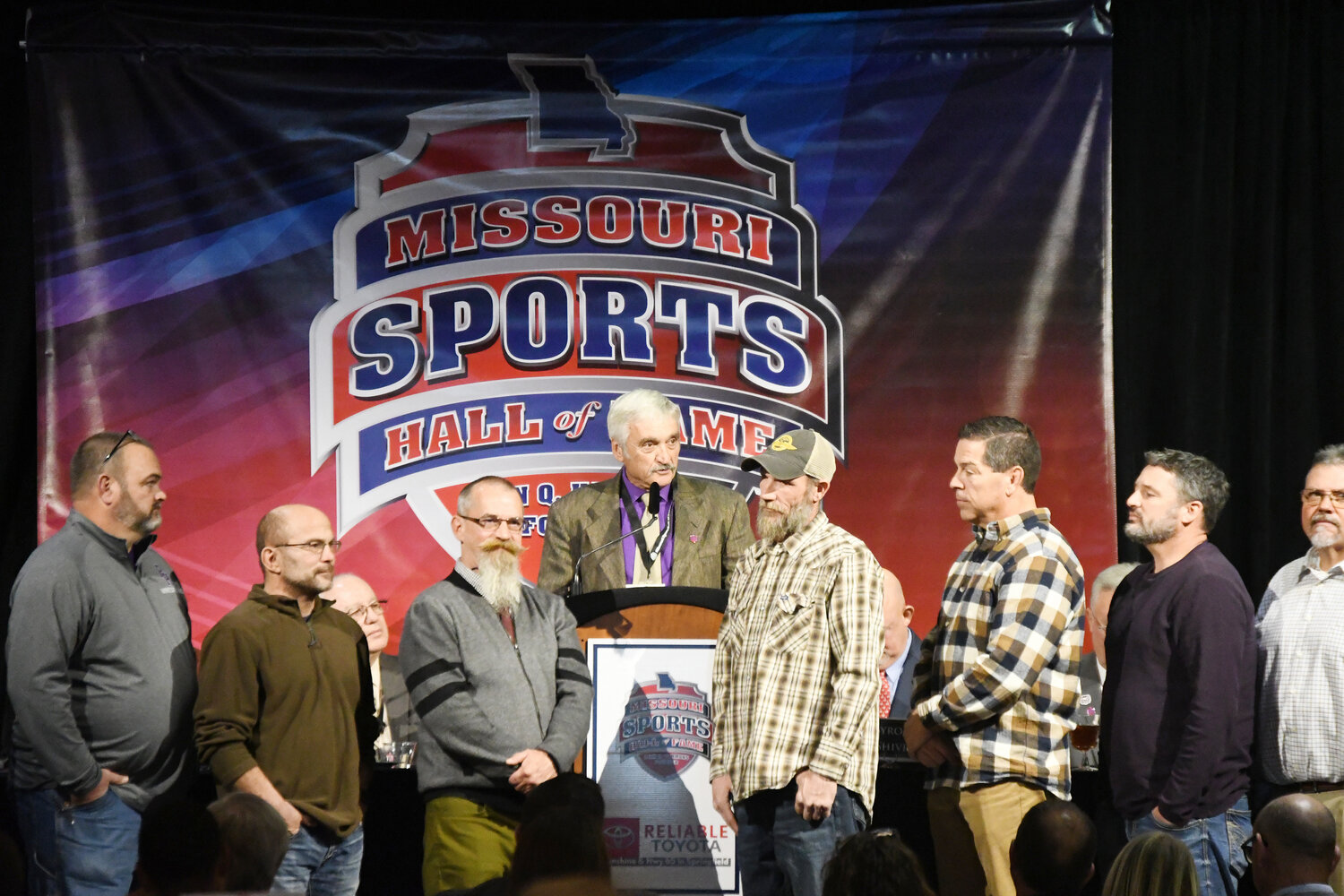 Former Pleasant Hill wrestling coach Steve Leslie gives his induction speech with nearly two dozen of his former wrestlers standing in front of him during last week’s luncheon at the Missouri Sports Hall of Fame in Springfield.