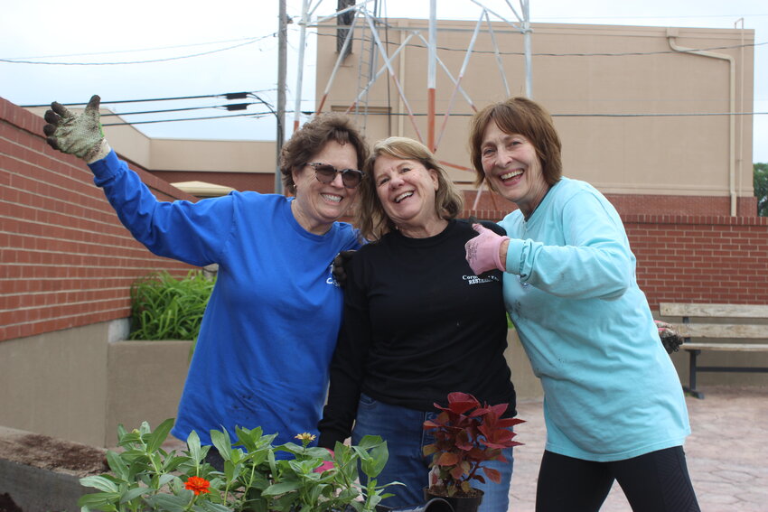 Jane Leitheiser, Debbie Long and Marsha Flummerfelt take time out for a little fun while planting flowers and other plants in downtown Ulysses recently. The trio volunteered their time and expertise to the project.