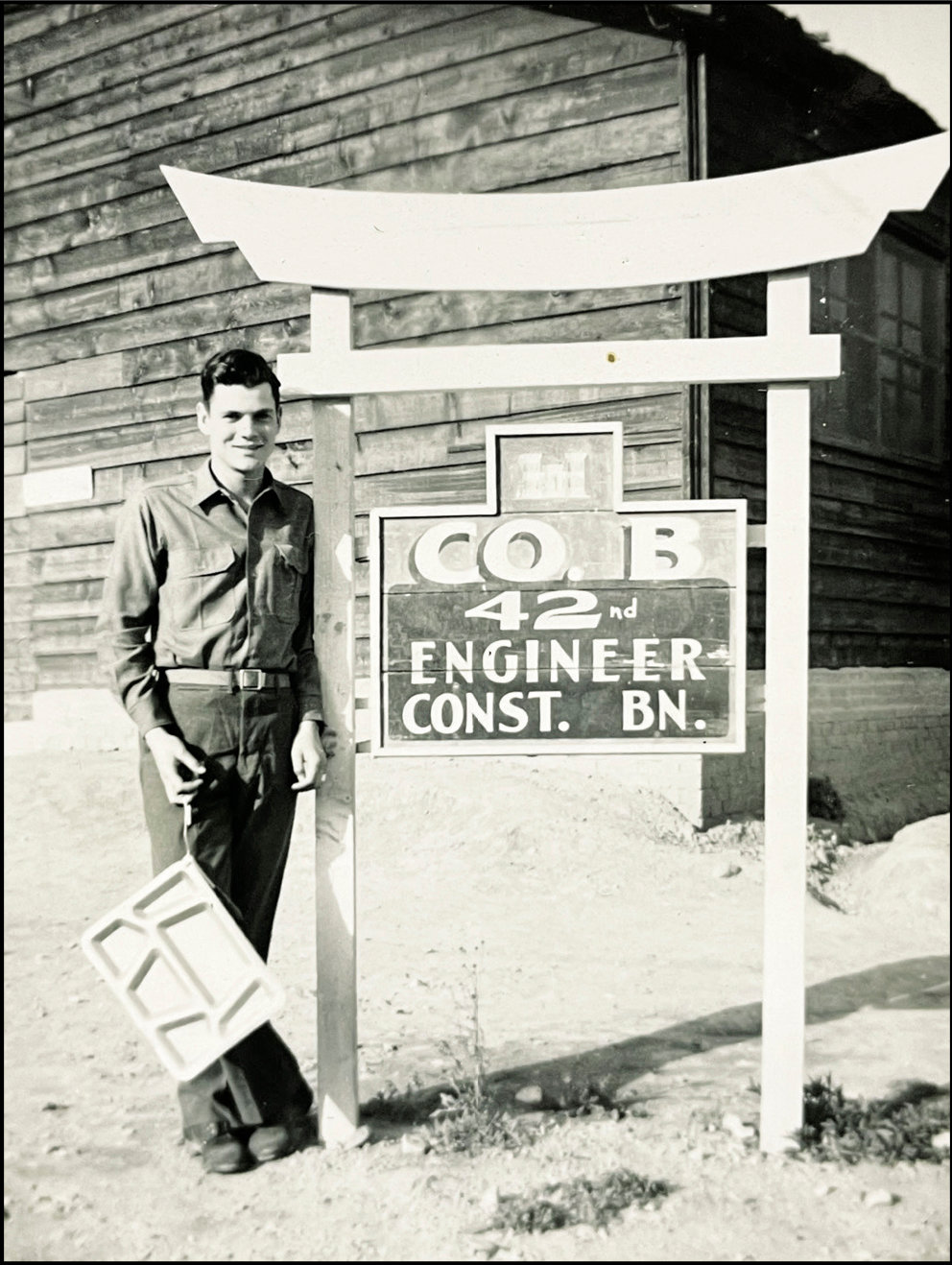 Kellye Hart, WWII veteran, stands by a sign where he was stationed in Pusan Korea. Hart served with Company B 42nd Engineer Construction Battalion.