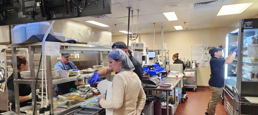 The kitchen at Confluence Health Hospital Central Campus is a busy one, making meals for patients, visitors, and staff each day. (L to R) Maria Nordstrom, Mike Miller, Michelle Harris, Victor Orquiz, Rocio Rivas, and Ruslan Garcia Renteria work to prepare for lunch.