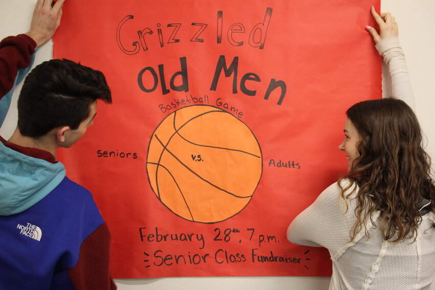 CHS Leadership students Scott Lindsay (12) and Rhetta Cummings (12) finish putting up promotional posters for Grizzled Old Men at Cascade High School.