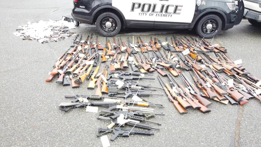 Returned lost or stolen firearms recovered by the Everett Police Department are laid out in a parking lot. The department started a program to get guns off the street called “guns for giftcards.”
