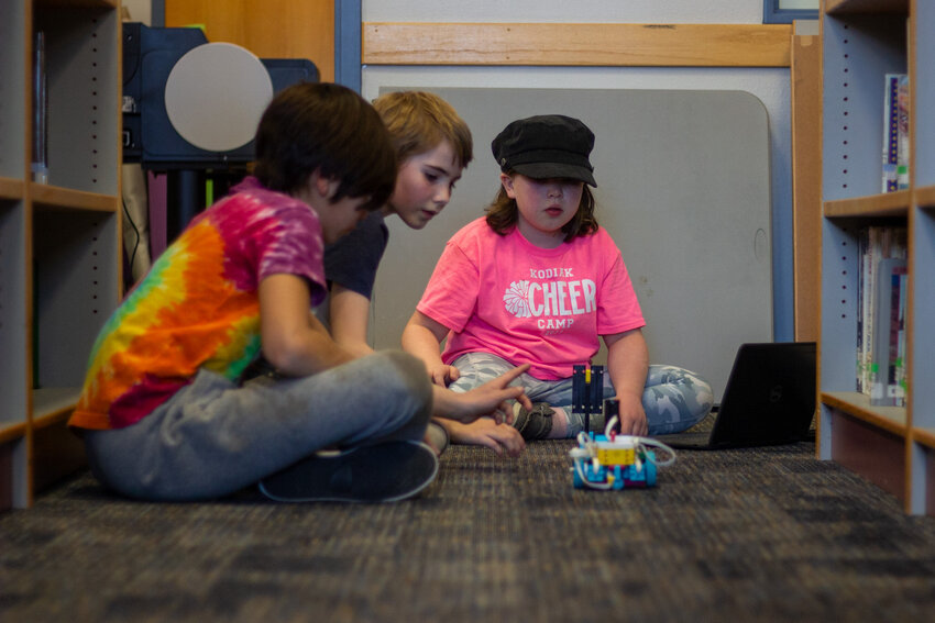 Maggie, Eero, and Micah code their robot to collect LEGO blocks in a relay-race fashion.