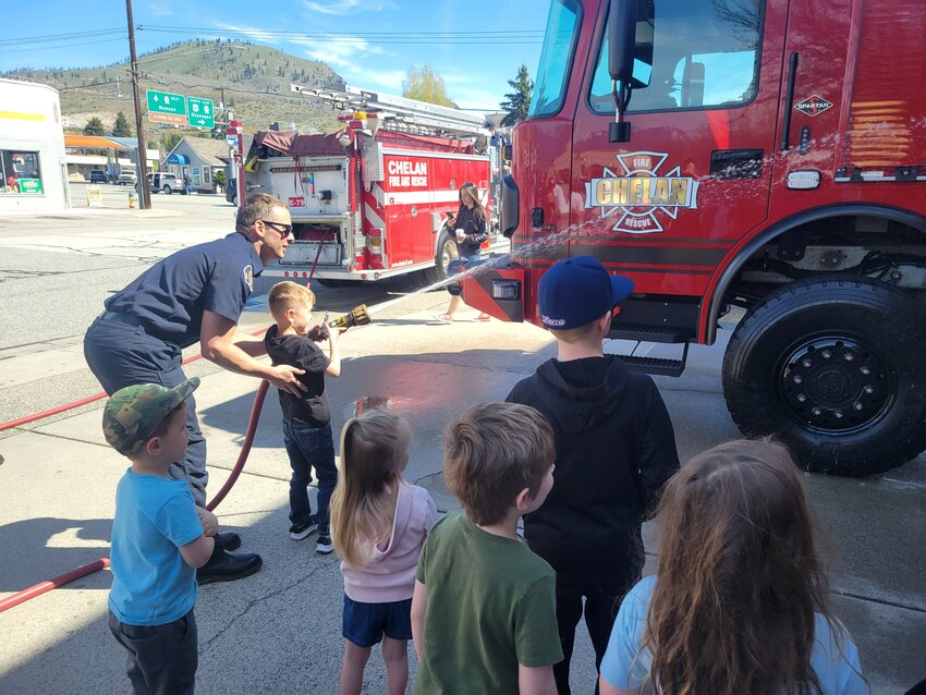 Children eagerly waited their turn to ‘wash down’ the new fire engine before it was pushed into its bay at the Chelan Fire Station on Wapato Avenue. Providing the water was the retiring E17 fire engine which has served the district for 16 years.