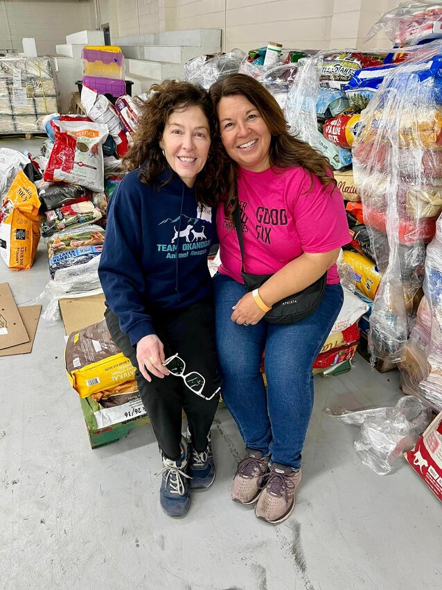TOAR Consultant, Jeanine Foucher, left, and Transport Coordinator, Stephanie Kraemer, pose among pallets of donated pet food.