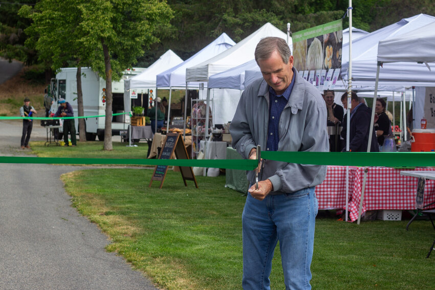 Mayor Carl Florea cuts the ribbon to one entrance of the first Leavenworth Community Farmers Market of the 2024 season. Chamber of Commerce Executive Director Troy Campbell cut a ribbon to the second entrance.