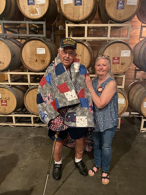 The tag sewn onto Dan Smith's Quilt of Valor details its dedication in Chelan on June 30, 2024. Created by the Thimblebuns quilting group, it was pieced by Sue Freden and bound by Tracy Shaw, exemplifying the community effort behind each quilt awarded to honor veterans' service and sacrifice.