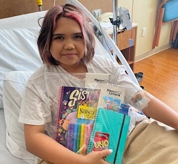 Paelyn Lueondee, 12, holds a Happy Letters Book Packet. In the spring, Paelyn teamed up with Happy Letters founder Traci Pierson to spread joy and encouragement to kids fighting cancer through a Happy Letters drive and a book drive.