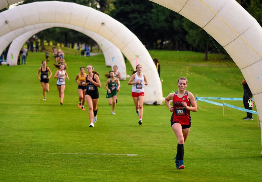 Cascade High School senior Harper Baker runs beneath the arches at the Nike Twilight XC Invitational last Saturday evening. Baker posted a season-best time at the race.