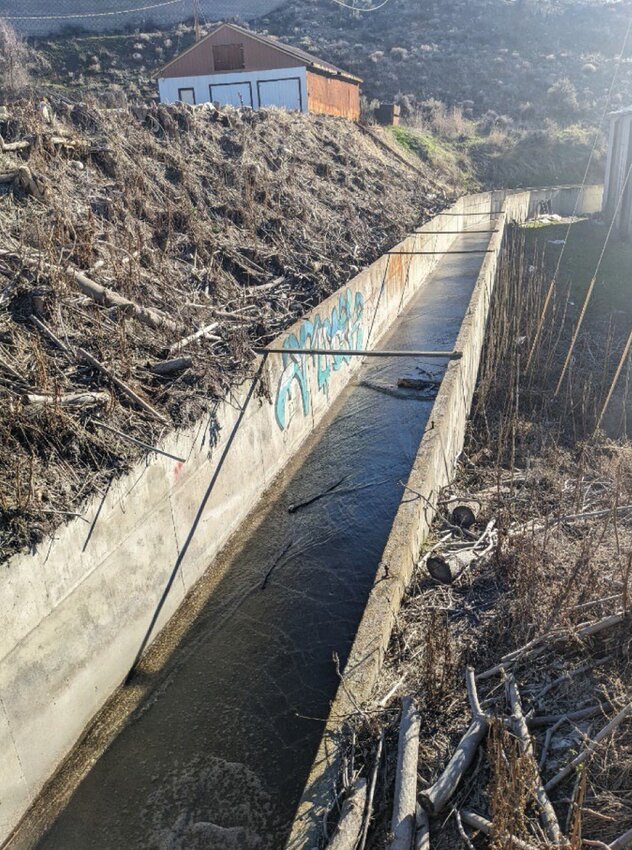 A concrete channel routes Swamp Creek water behind a warehouse.