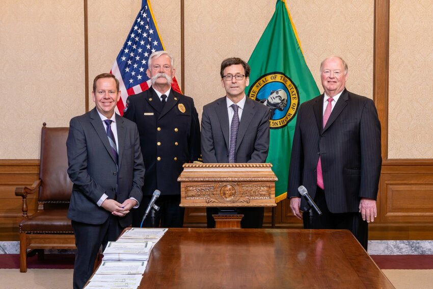 Governor Bob Ferguson (third from left) signs House Bill 1156 into law on April 16, 2025, as Rep. Mike Steele (far left), Chelan County Fire District #5 Chief Arnold Baker (second from left), and Rep. Joe Schmick 9th Dist. (far right) look on during the ceremony in the Governor's Office in Olympia. The bill grants volunteer firefighters access to the state's deferred compensation program.