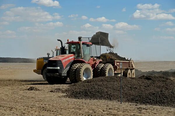 A loader distributes biosolids on an agricultural field.