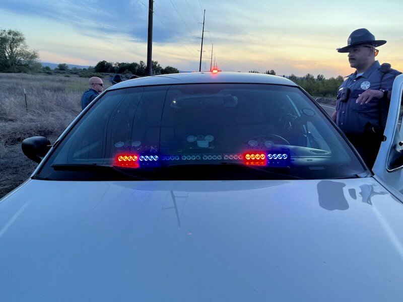 A Washington State Patrol trooper stands near a silver Ford Crown Victoria equipped with red and blue dash-mounted lights, which a Spokane man allegedly used in an attempt to impersonate law enforcement during two traffic stop attempts near Leavenworth on May 8.