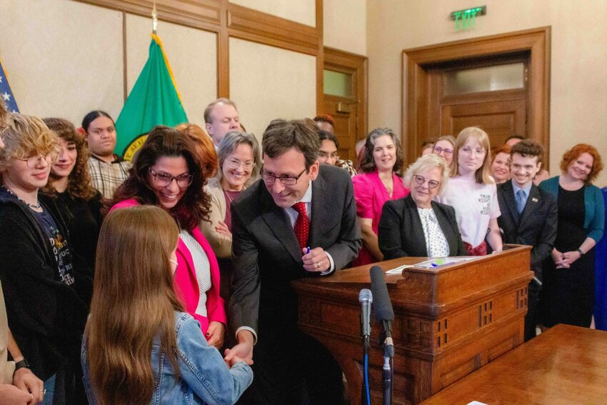 Gov. Bob Ferguson hands over one of the pens he used to sign House Bill 1296, the ‘students bill of rights’ to a child who attended the bill signing.