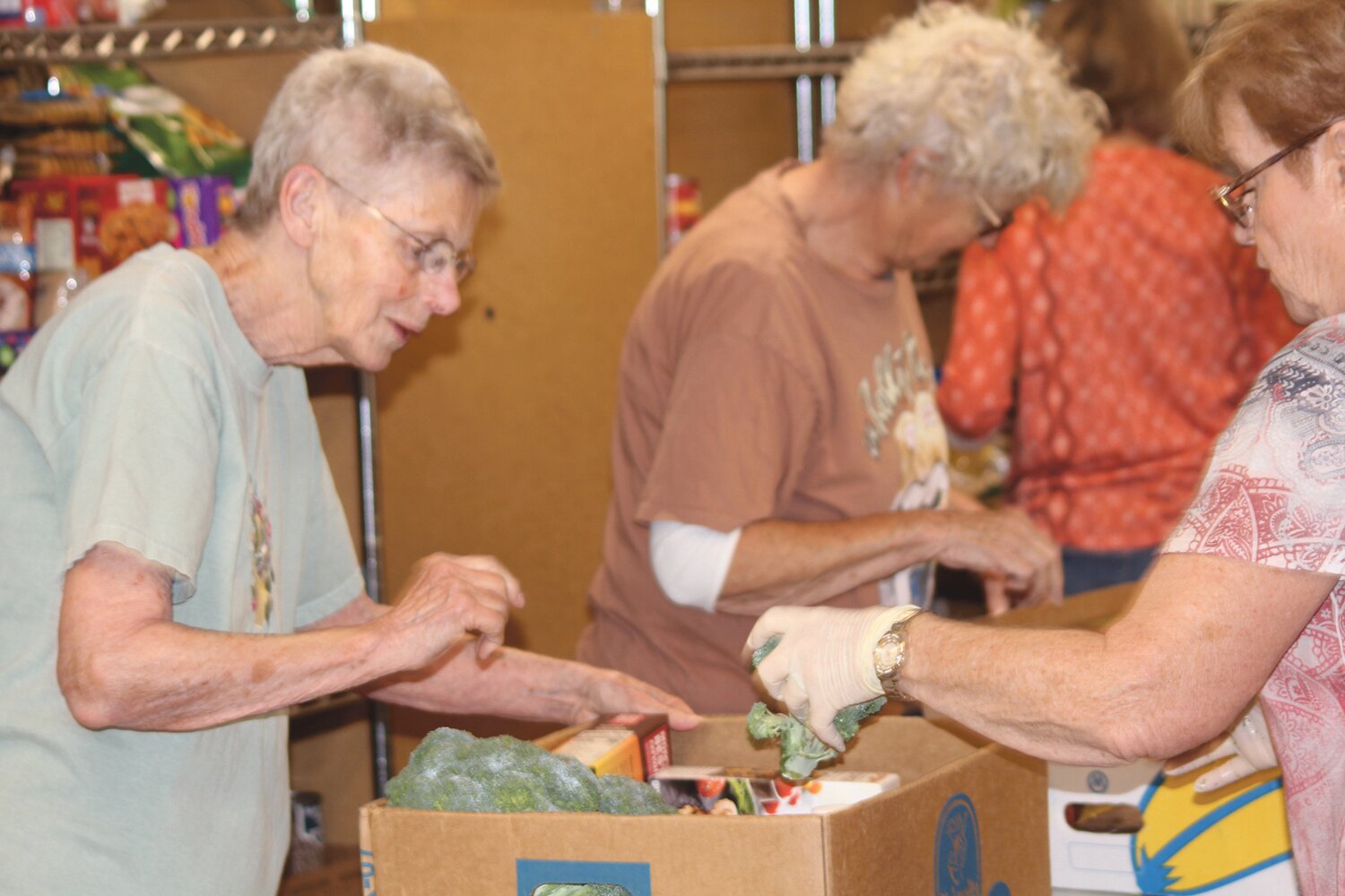 Matthew Ockinga/LCM
Volunteers at the Lake Chelan Food Bank place fresh vegetables into to-go boxes on July 2. Each family receives one box containing 40-50 pounds of food.