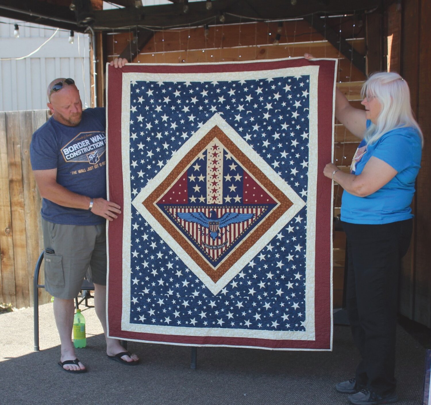 Doug Kirk displays his veterans quilt with the help of quilter Patti Cockfield.