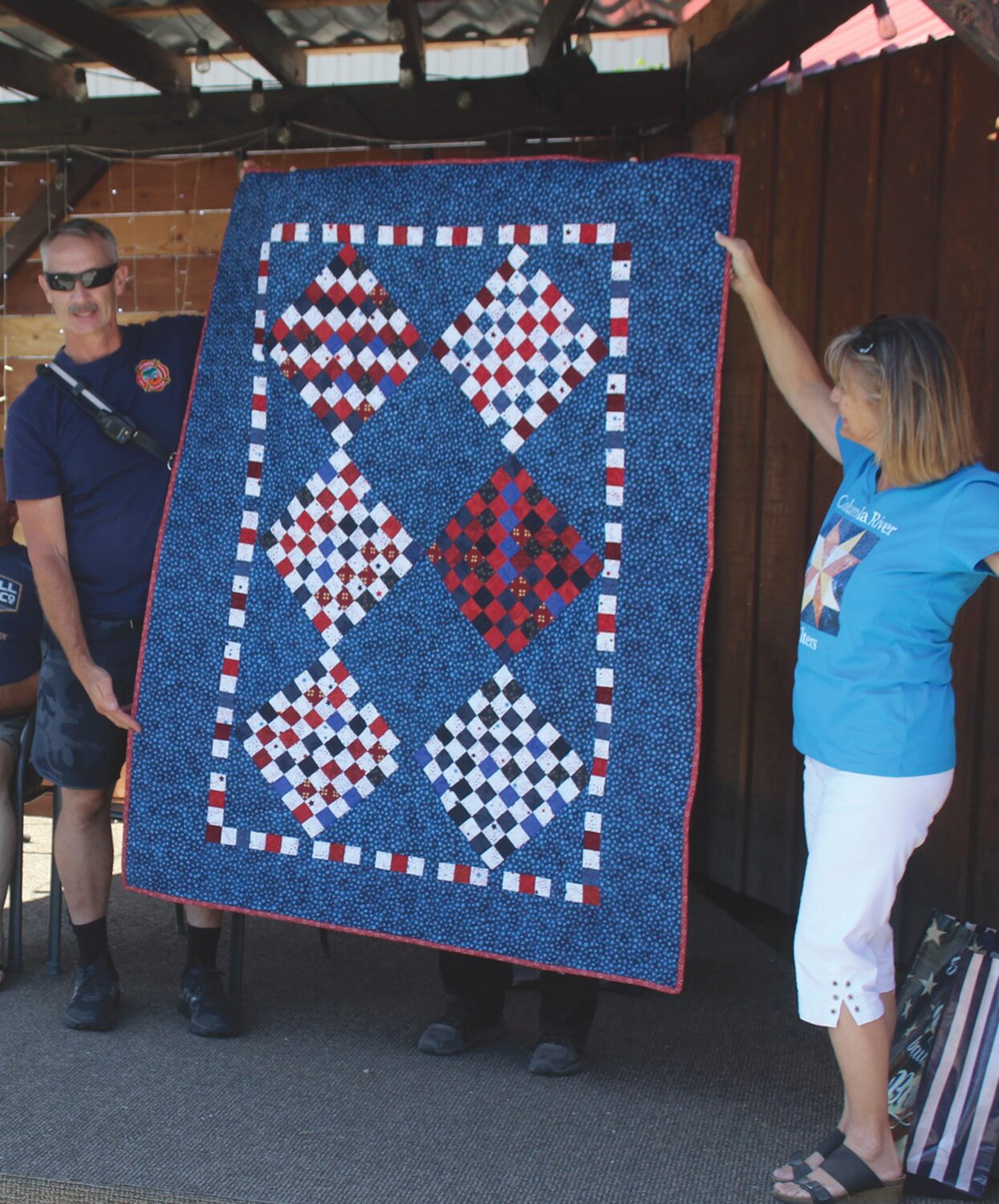 Keith Zwiegle accepts a quilt from Nancy Woods on behalf of his father, Bill Zwiegle.