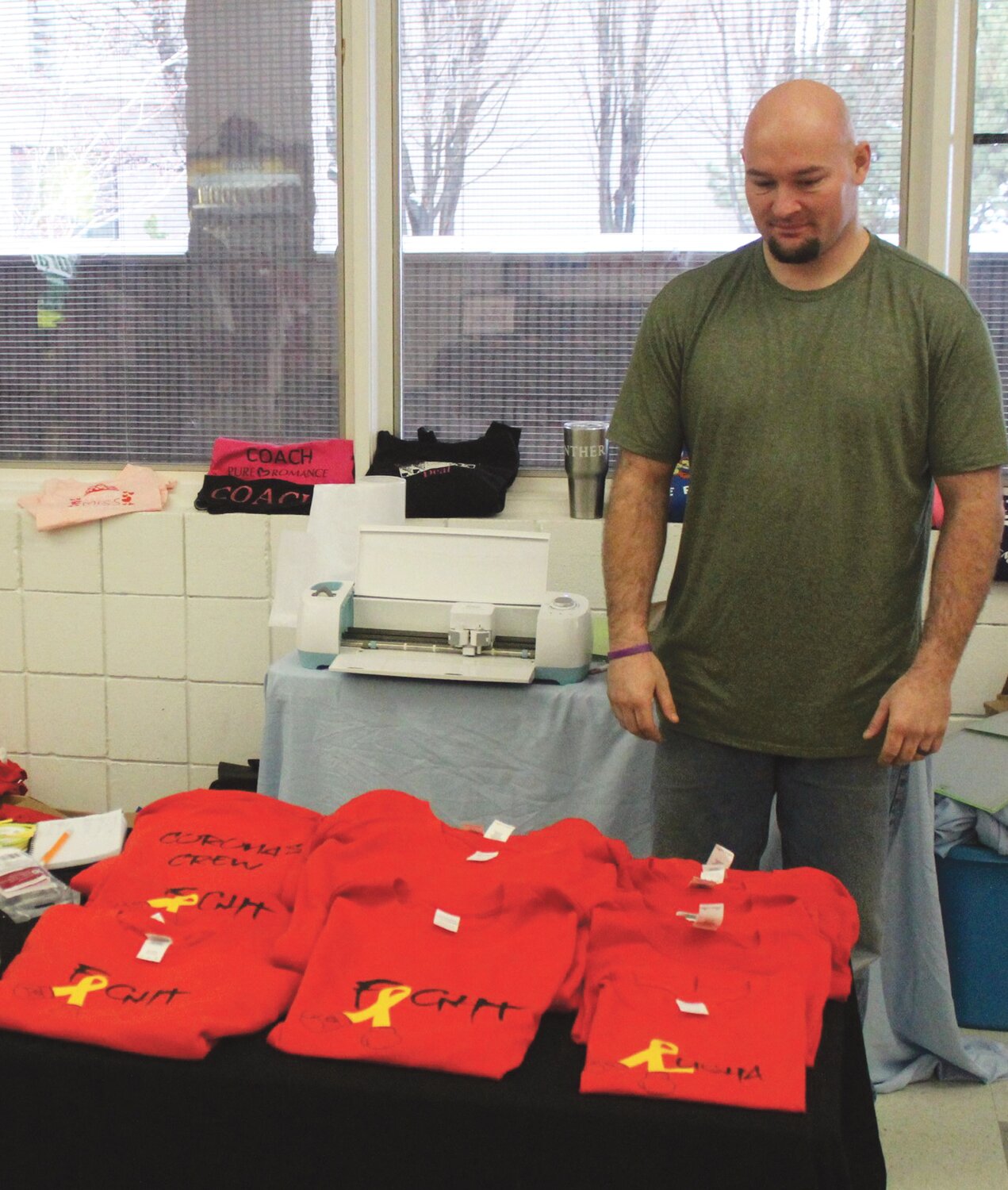 Sean Madsen, owner with wife Mistie of M&S Custom Vinyl in East Wenatchee, stands next to a display of red T-shirts designed for the Yahir Corona fundraiser.